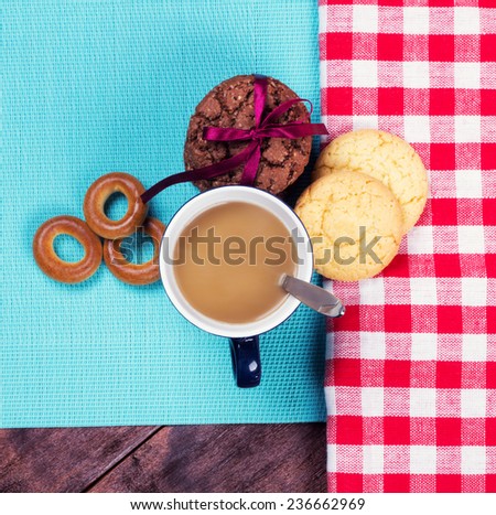 A cup of coffee on the table next to the pastries. Bagels and cookies next to a cup of coffee.