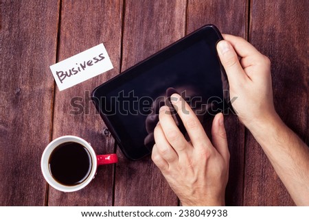 Male hand with tablet pc and cup of coffee on the table. A young man with a tablet  in his hand at the table. Business concept, business solutions and work flow.