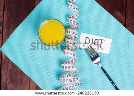 A glass of orange juice, fork, measuring tape and a note. The concept of diet and weight loss. The pursuit of harmony of the body. A strict diet for weight loss.