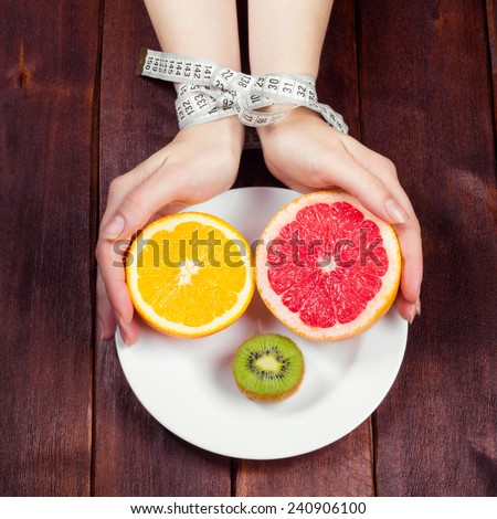 Cut fruit on a plate. Related by measuring tape Female hands and a plate of fruit. Dietary restrictions. The concept of a  fruit diet. Low-calorie food. The rapid loss of excess weight.