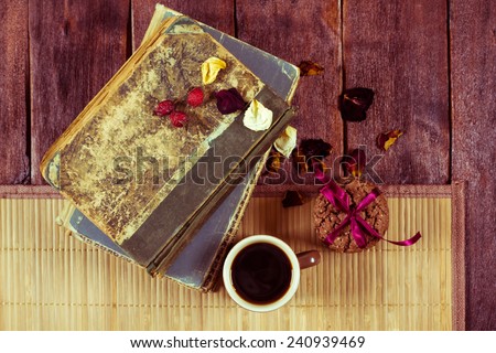 Vintage composition with a cup of coffee and old books. Books, chocolate chip cookies, rose petals and a small cup of coffee. Theme of reading books, writing and literary criticism.
