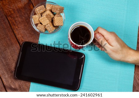 The idea of ??office work, freelancing, wireless technologies, lunch. Black coffee. Cup of coffee, waffles, tablet and the man's hand. Office worker or businessman with a cup of coffee.