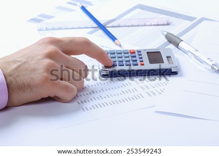 Accountant. Man\'s hand and calculator. Finance department, accounts, accounting documents. Pens, pencils, papers, ruler and calculator. The man with the calculator. Office worker. Toned image.