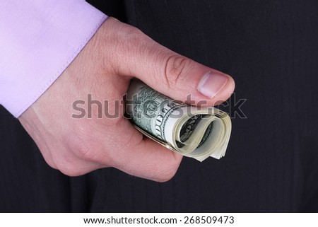 Hand with money. A man in business clothes with money in hand. A fist full of money. Dollar bills clenched in his hand.