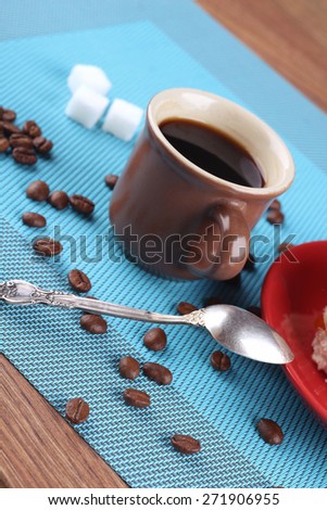 Espresso coffee on the table. Black strong coffee on the table. To drink coffee. A Cup of coffee on the table. Coffee beans, refined sugar, spoon and saucer on the table.