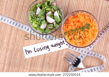Salad of carrots, salad greens and radishes. Glass salad bowl. Delicious a salad diet. Measuring tape, banner \