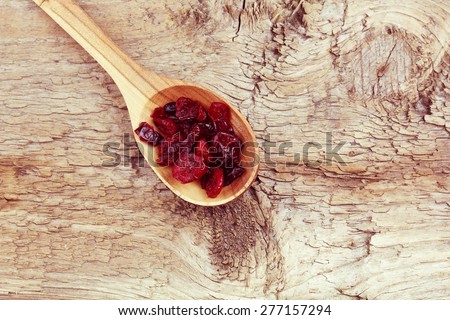 Wooden spoon with dried berries on the table. Spoon with berries. Dried cranberries on the table. The view from the top.