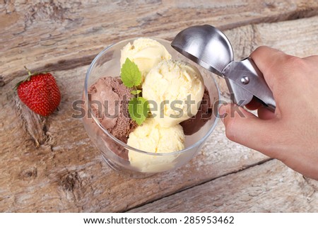 Creamy vanilla and chocolate ice cream. A delicious dessert. Spoon for ice cream. Male hand with a spoon for ice cream. The ice-cream bowls with ice cream. Ripe berry and ice cream.