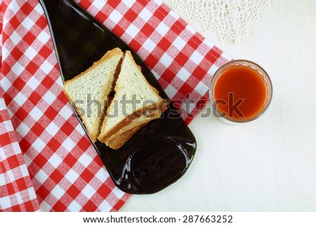 Toast with toppings and a glass of juice on the table. The checkered tablecloth and the food on the table. A delicious lunch. Crispy toast on the table. A glass of tomato juice and crispy toast.