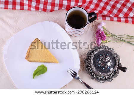 A delicious cake for dessert. Lemon pie, cheesecake. A piece of pie on the plate. Cup of black tea, a sugar bowl and a dessert. In the cafeteria, in the restaurant. The food and drink.