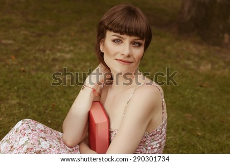 Girl with the book. Hugging the book. Portrait of a beautiful girl. Woman\'s portrait. Relax in the Park. Girl in sundress on the street. Tinted photo. Young woman in the park. To read book. Vintage/
