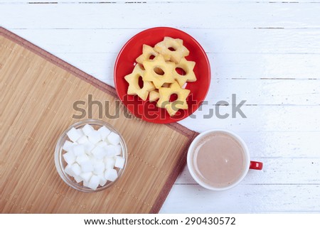 Cup of hot chocolate, sugar bowl and a plate of biscuits. Sweet pastries and a cup of cocoa. Dessert, snack, lunch, pastries. Snack bar, restaurant, coffee shop. Top view. Table with food.