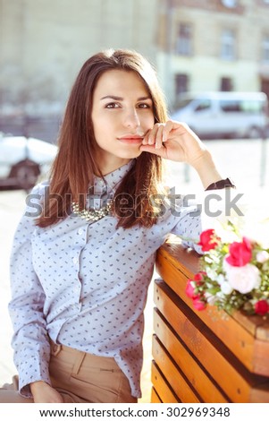 Beautiful stylish girl on the street. Business fashion, fashion trends, street look, business casual, street fashion. Portrait of a young woman in the street. Girl with flowers.