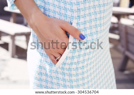 Tanned girl\'s hand with blue nail. Hand in pocket dress. Blue dress. Item of clothing. Stylish look. Dress-case. Summer wardrobe. Young woman in dress.