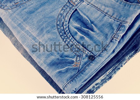 Stack of blue jeans of different colors. Stack of clothes. Many jeans. Toned image. Jeans pocket. A bunch of pants, men\'s pants.
