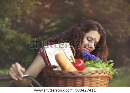 Beautiful woman cyclist with a basket. Bicycle Basket. To buy food. Food, a bouquet of flowers. Beautiful girl with retro bicycle. Products on a bicycle. Gastronomy. Healthy food.