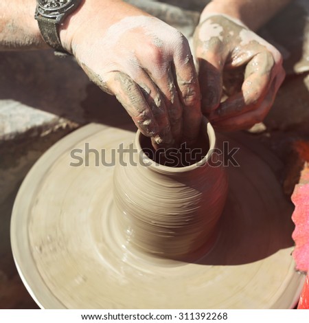 Men\'s hands. Potter at work. Creating dishes. Potter\'s wheel. Dirty hands in the clay and the potter\'s wheel with the product. Creation. Working potter.