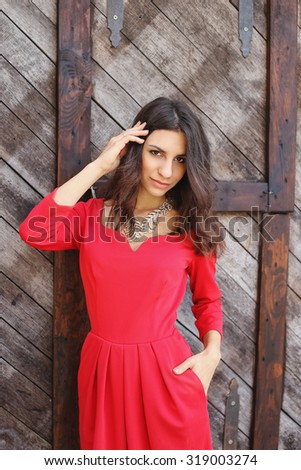Self-confident sexy woman. Young woman with sexy look. The girl on the background of wooden wall. Gypsy, a Spaniard. Seductive girl. Brunette in a dress and necklace.