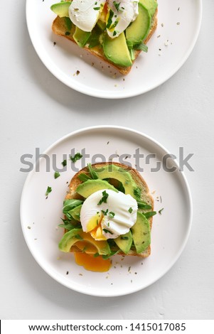 Poached eggs on toasted bread with avocado, rukola and herbs on light background. Top view, flat lay Zdjęcia stock © 
