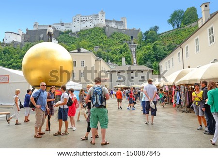 SALZBURG, AUSTRIA-JULY 30: Kapitelplatz on July 30, 2013 in Salzburg, Austria. Kapitelplatz is square in Old Town of Salzburg. Here is located large sculpture of man standing atop a large gold ball.