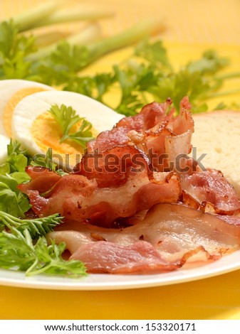 Breakfast with bacon and eggs on white plate