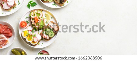 Sandwiches with meat, vegetables, seafood. Assortment open sandwiches on light stone background with free text space. Tasty healthy snack. Top view, flat lay.