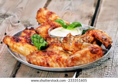 Baked chicken wings with sauce on wooden table, close up view