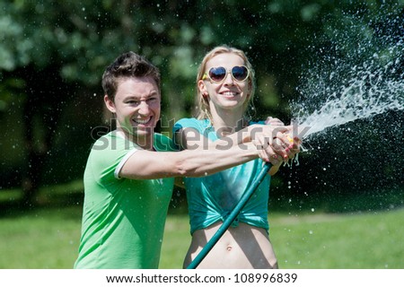 Young man and woman have fun getting wet playing with water spray