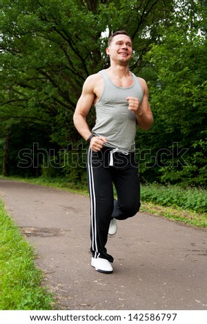 Man in black pants runs on the road in the park