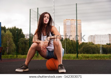 Sexy Woman Sitting On Basketball On Sports Playground