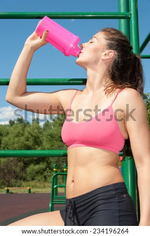 Sport Woman Runner rest drinking water, time out to drink cold water on playground
