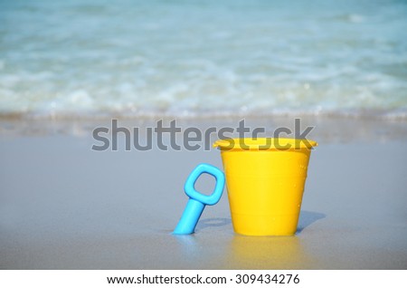 sand bucket and shovel in the sand by the water