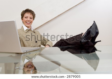 Causal businesswoman working on computer with her feet up on desk.