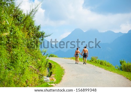Behind of couple hikers enjoying on the small road from a mountain