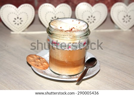 cup of coffee latte macchiato with cream, cinnamon powder and biscuit, shallow depth of field