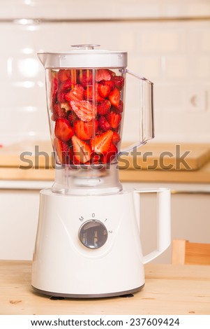 fresh strawberries in white Blender on a wooden table. kitchen