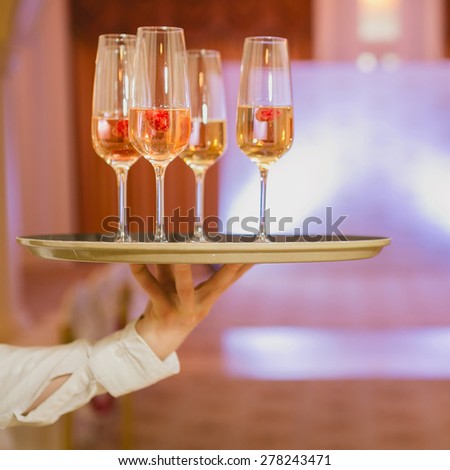 Waiter serving champagne with strawberries on a tray