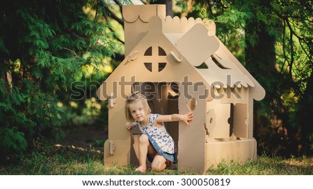 girl playing cardboard house in a city park on a sunny day