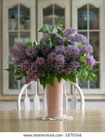 Vase of lilacs on a wooden farm table.