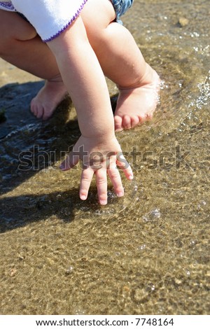 hands and feet of a toddler in shallow water