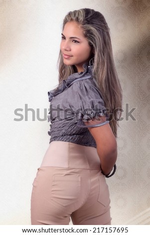 Photo of a beautiful adolescent with her flyaway hair and using pair of pants beige gray blouse, with her look toward the side
