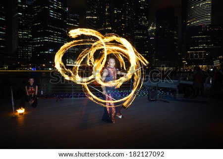 SINGAPORE - MARCH 15, 2014: Fire Dancer street performance using fire staff, at Marina Bay.