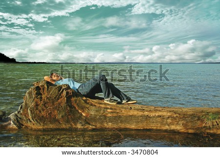 A woman lies on  a trunk in the water on a lake. The unique keyword for this collection is: lake77