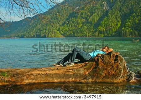 A man lies on  a trunk in the water on a lake. The unique keyword for this collection is: lake77