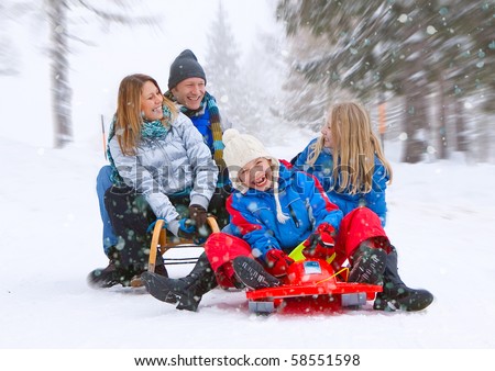 young funny family is sledging in winter-landscape
