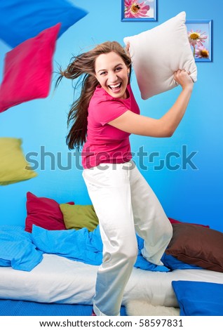 young teenage-woman is making a pillow-fight