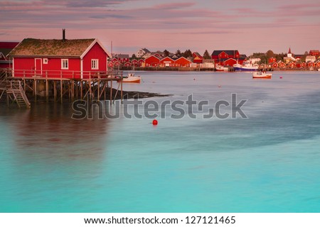 Typical red rorbu fishing hut in town of Reine on Lofoten islands in Norway lit by midnight sun