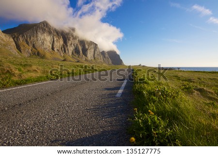 Scenic coastal road under the cliffs of island Vaeroy on Lofoten, Norway