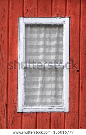 Small white window frame on a red wooden house