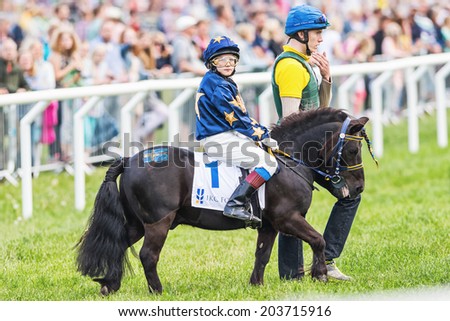 STOCKHOLM - JUNE 6: Pony racer warming up with her trainer and horse before the start of childrens race at Nationaldags Galoppen. June 6, 2014 in Stockholm, Sweden.